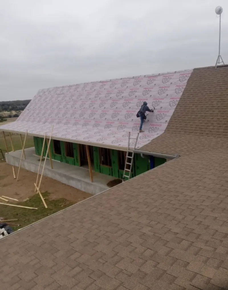 Worker preparing underlayment for a metal roof installation in Manhattan